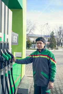 Smiling worker at the gas station, while filling a car