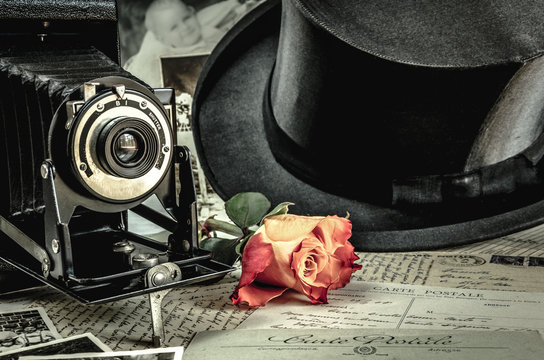 Still life with a vintage camera, rose and elegant top hat.