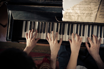 Man and woman are playing piano together