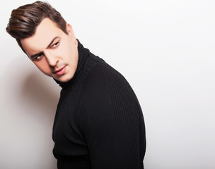 Studio portrait of young handsome man in black knitted sweater. 