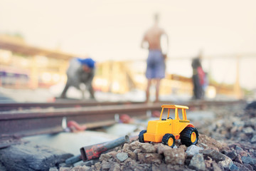 Yellow tractor toy model on workers background. Shallow depth of