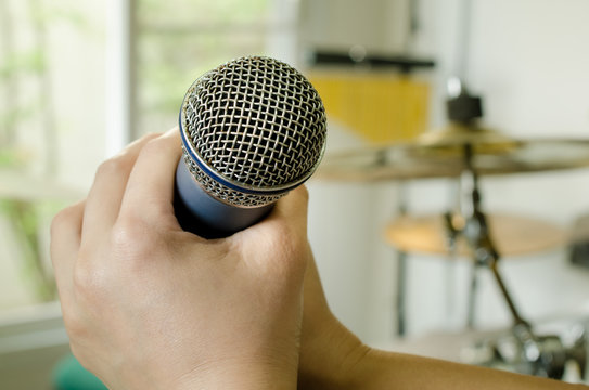 Hands holding a microphone in music room