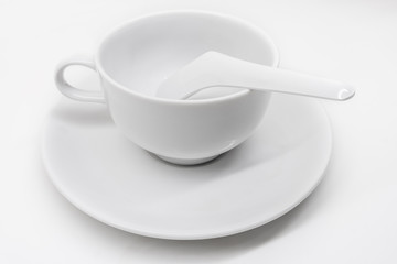 A white ceramic cup with saucer and soup spoon