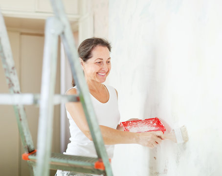 Happy Mature Woman Paints Wall