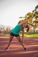 Obraz premium female athlete stretching on a running track