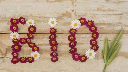 Obraz na płótnie Canvas Wort BIO aus Blüten mit Getreideähren auf Holz