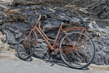 Naklejka premium rusted bycicle on rocks background