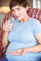 Pregnant woman taking a vitamin tablet