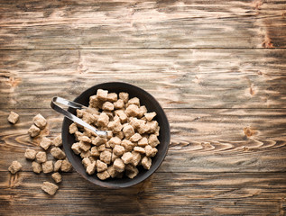 Cubes of cane sugar in the bowl on wooden table.