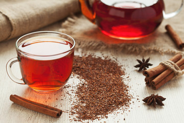 Healthy african rooibos tea in glass cup with spices on vintage