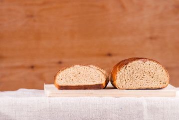 Cut loaf of fresh bread on burlap on wooden table