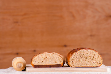 Cut loaf of fresh bread on burlap on wooden table