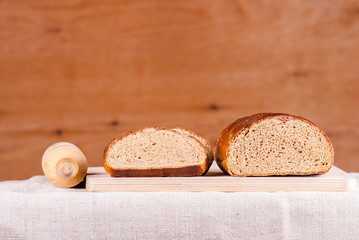 Cut loaf of fresh bread on burlap on wooden table