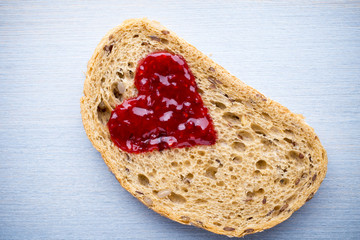 Grain slice of bread with jam heart shape.