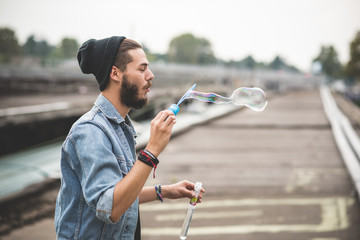 young handsome bearded hipster man blowing bubbles soap - obrazy, fototapety, plakaty