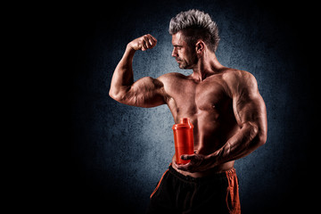 Fototapeta na wymiar young handsome man with strong muscles, protein drink after trai