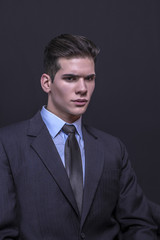 Young businessman posing in suit on a black background