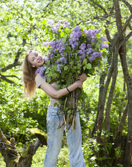 Fototapeta premium happy young woman in park with a big bouquet of a lilac