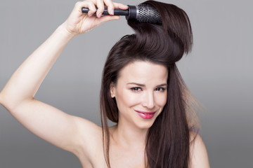 Fototapeta premium Gorgeous girl smiling and holding a hair brush in her hair