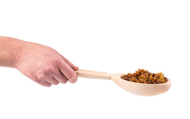 Hand holding wooden spoon with raisins.