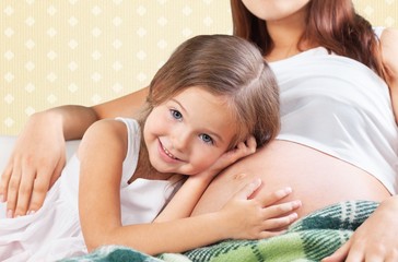 Pregnant. Kid girl listening pregnant mother's belly
