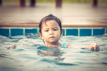 Cute little girl in swimming pool in vintage color style