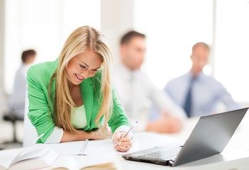 attractive businesswoman taking notes in office