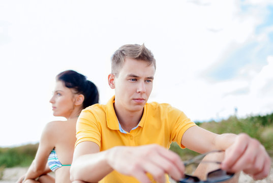 Unhappy Couple Sitting On Beach