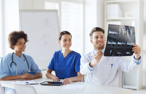 group of happy doctors discussing x-ray image