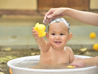 Baby bathing in the white tub, baby playing yellow duck