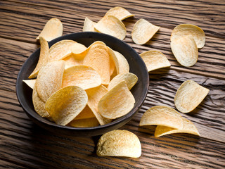 Potato chips on a wooden background.