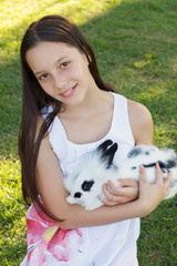 Cute beautiful smiling teen girl holding at white-black rabbit