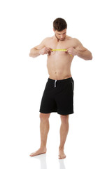 Fototapeta premium Muscular man measuring his chest.