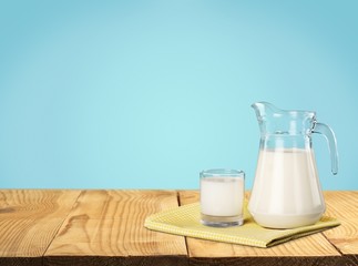 Milk. A glass of milk and a milk jug on plaid tablecloth.