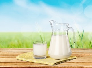 Milk. A glass of milk and a milk jug on plaid tablecloth.