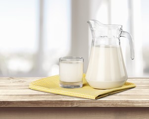 Milk. A glass of milk and a milk jug on plaid tablecloth.