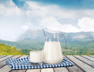 Milk. A glass of milk and a milk jug on plaid tablecloth.