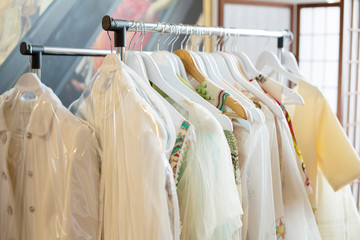 Set of light colored dresses on a wooden hangers