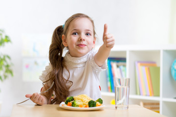 Obraz na płótnie Canvas child eats healthy food showing thumb up
