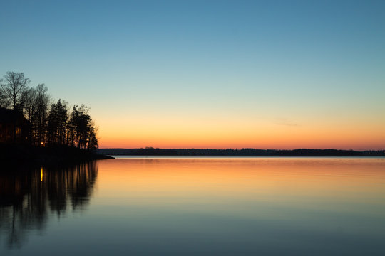 Cabin on the point reflecting in the lake with spring sunset col