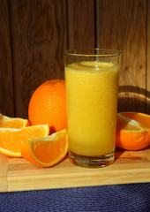 A glass of orange juice and orange slices.
