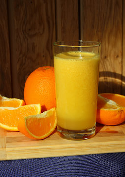 A glass of orange juice and orange slices.