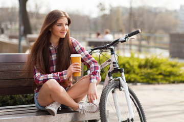 Young woman drinking coffee on a bicycle trip