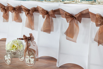 Row of wedding chairs with brown ribbons.