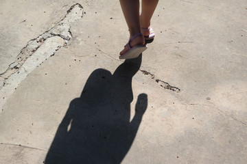 Frauenfüße mit Schlappen auf warmen Asphalt