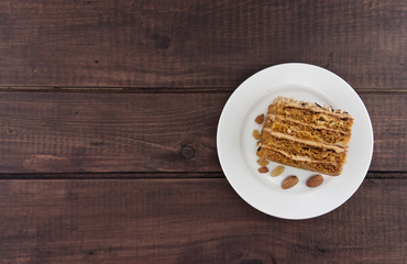 Cake slice with nut on plate on wooden table, top view.