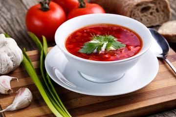 Borsch with bread on a wooden background.