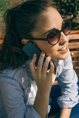 Young beautiful woman with sunglasses talking with her phone sit