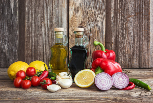 Olive oil, balsamic vineger and vegetables on wooden background