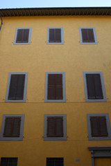 Fototapeta na wymiar Facciata palazzo giallo con finestre e persiane